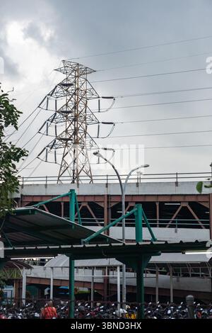 Jakarta, Indonesien - 30. Januar 2025: Ein großer Stromturm ist im Hintergrund einer überfüllten Stadtstraße zu sehen. Der Himmel ist bewölkt und die Atmosphäre ist tu Stockfoto