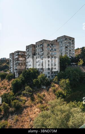 Fotos von alten Wohngebäuden aus Betonplatten aus den 1970er Jahren in Tiflis, Georgien. Diese ikonischen Beispiele brutalistischer Architektur aus der Sowjetzeit spiegeln den krassen, utilitaristischen Stil jener Zeit wider. Rohtexturen, sich wiederholende Geometrien und verwitterte Fassaden sprechen vom historischen und sozialen Kontext der Stadtentwicklung während der Sowjetzeit. Stockfoto