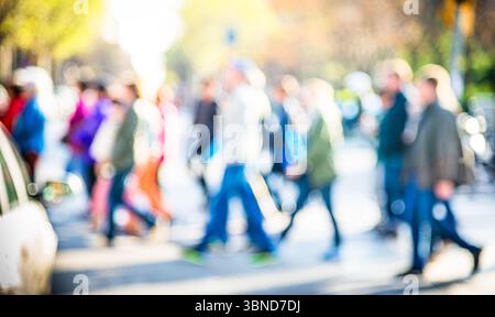 Verschwommenes Bild eines belebten Fußgängerübergangs mit Menschen, die bei Tageslicht laufen Stockfoto