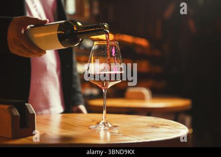 Glas wird in der Weinbar mit Rotwein gefüllt Stockfoto