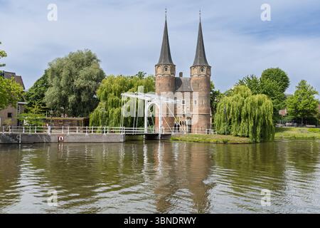 Das historische Oostpoort (östliches Tor) in Delft mit seinen berühmten Zwillingstürmen und der malerischen Zugbrücke über das ruhige Wasser. Stockfoto