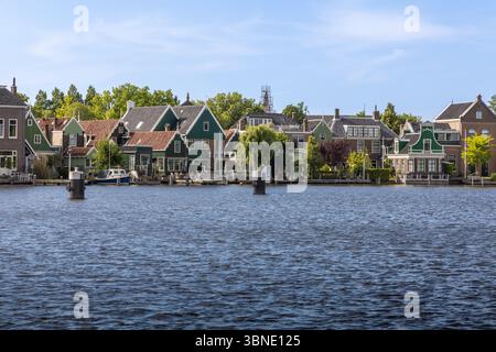 Dieses malerische Foto zeigt traditionelle, grün bemalte holländische Häuser, die das ruhige Wasser von Zaanse Schans Zaandam säumen, und erinnert an die klassische Schönheit von H Stockfoto
