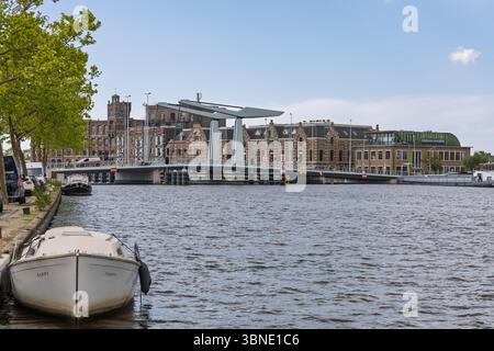 Moderne Zugbrücke über einen Kanal in den Niederlanden mit historischen Gebäuden, Booten und ruhigem Wasser an einem klaren Tag in einer malerischen städtischen Umgebung. Wormer, Netto Stockfoto