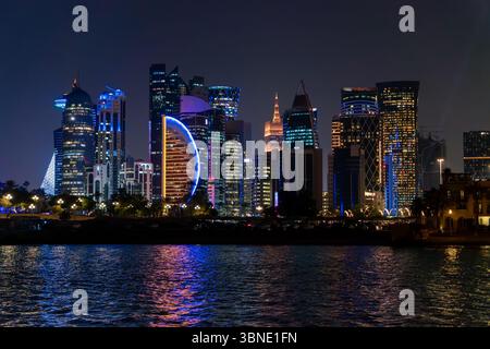 Die Skyline von Doha und traditionelle Holzboote auf dem Wasser während der Ruhe. Nachtszene, wunderschöner Panoramablick auf Doha vom Meer bei Nacht. Stockfoto