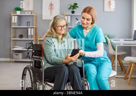 Frau Krankenschwester lehrt weibliche Seniorenbehinderte Frauen, wie man Gesundheit App auf Smartphone herunterlädt Stockfoto