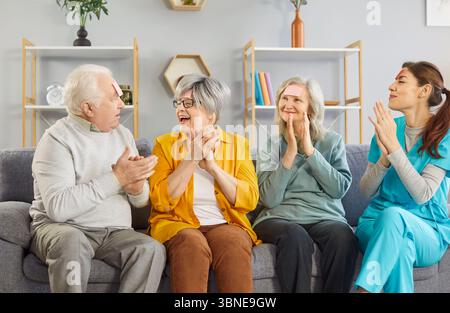 Seniorinnen und Senioren aus dem Altersheim und ihre Betreuerin haben Spaß miteinander und spielen Spiel Stockfoto