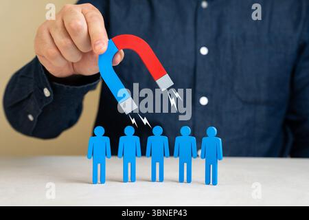Ein Mann mit einem Magneten zieht Menschen an. Charisma der Führung. Kunden gewinnen oder einstellen. Personalbeschaffungsstrategien, Unternehmenskommunikation, Kundenakquise Stockfoto