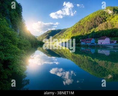 Ruhiger Fluss mit leuchtend blauem Himmel mit Wolken und Bergen Stockfoto