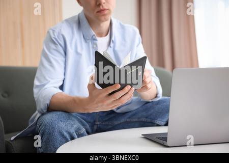 Mann mit Pass in der Nähe des Laptops zu Hause, Nahaufnahme Stockfoto