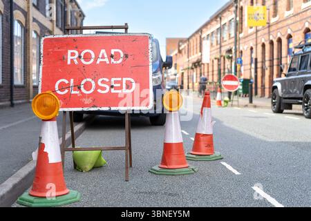 Nahaufnahme eines rot-weiß-Schilds für die geschlossene Straße auf einer Straße mit Kegeln und Lichtern. Stockfoto