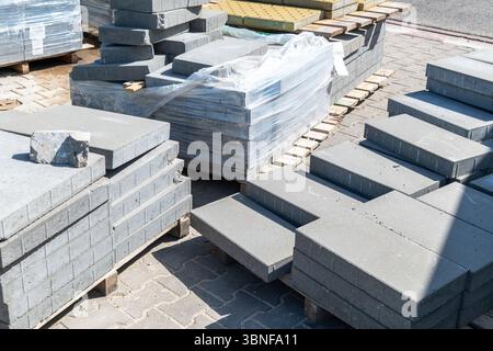 Graue Betonplatten, die im Freien auf Holzpaletten gestapelt sind. Stockfoto