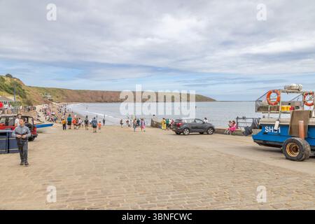 Besucher treffen sich auf Coble Landing, der Slipway, die zum Strand und der weiten Kurve der Filey Bay führt. Reise und Tourismus, North Yorkshire, Großbritannien. Stockfoto