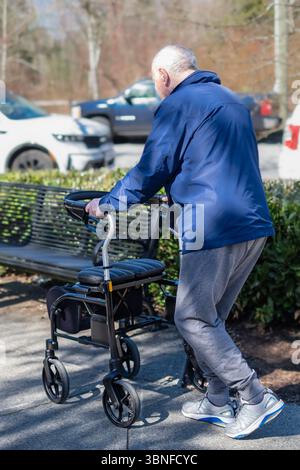 Das Konzept der Mobilität älterer Menschen. Ein älterer Mann läuft die Straße entlang. Rentner gehen an einem Walker vorbei. Behinderte Person, die mit Gehhilfen im Freien läuft. S Stockfoto