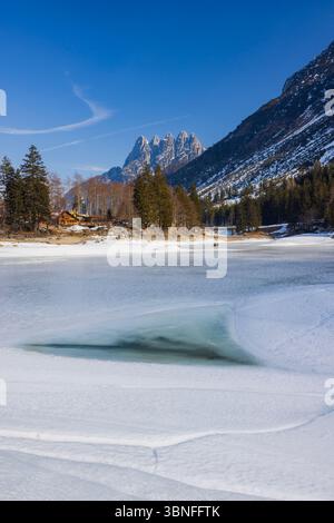 Ruhige Winterlandschaft mit einem gefrorenen See und weit entfernten Bergen in Tarvisio, Italien Stockfoto
