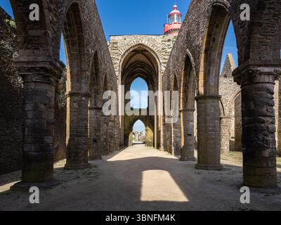 Innenansicht der Abtei von Saint-Mathieu de Fine-Terre in der Bretagne, Frankreich, mit Steinbögen und Leuchtturm, die unter klarem Himmel ragten. Stockfoto