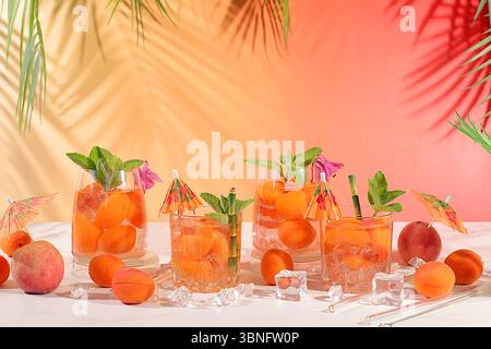 Eistee oder Cocktail mit Pfefferminze und Aprikosen, erfrischendes Sommergetränk. Zwei Gläser mit Pfirsichfrucht-Limonade auf einem hellen Tisch, Entgiftungsdiät Stockfoto