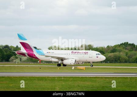 Passagierjet auf einer Start- und Landebahn, mit dem Emblem von Eurowings, Wolken über dem Kopf, die Luftfahrt und den Transport darstellen. Stockfoto
