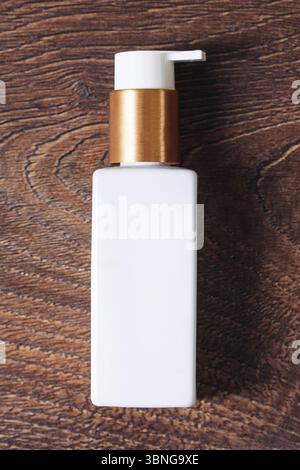 Weiße Kosmetikflasche. Pumpenspender auf Holzuntergrund. Sauberes Kosmetik-Hautpflegeprodukt. Minimalistisches Verpackungsdesign. Hygiene und Kurbehandlung. Stockfoto