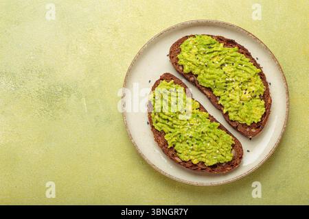 Zwei Scheiben Avocado Toast mit Sesamsamen auf Roggenbrot, Blick von oben auf hellgrünem Hintergrund Stockfoto