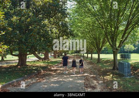Fußgänger schlendern auf einem baumgesäumten Weg im Maymont Park, Richmond, Virginia, und genießen die natürliche Schönheit und die ruhige Landschaft des historischen Parks. Stockfoto