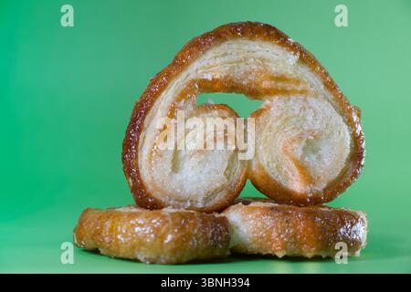 Herzförmiges palmier-Blätterteiggebäck mit einem leuchtend grünen Hintergrund Stockfoto