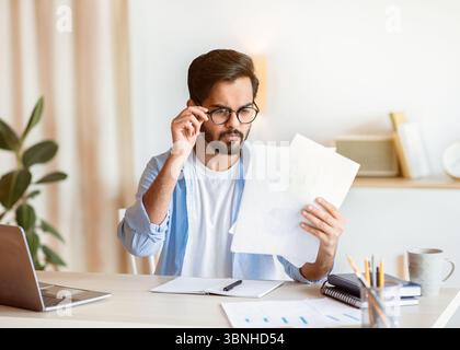Betroffener Arabischer Geschäftsmann In Brillen, Der Finanzdokumente Am Arbeitsplatz Liest Im Büro Stockfoto