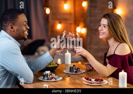 Romantisches Multiethnisches Paar Klinkende Gläser Mit Wein Auf Date In Restaurant Stockfoto