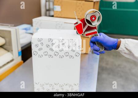 Nahaufnahme der Hände des Lagerarbeiters, die während der Verpackung einen Karton kleben. Stockfoto