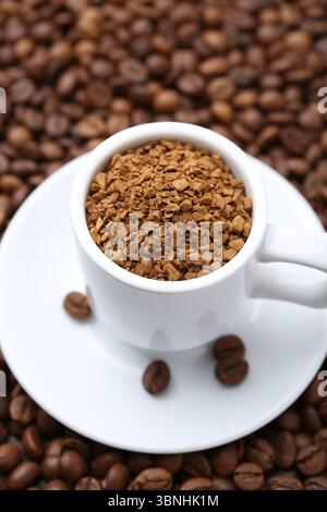 Tasse mit granuliertem Instantkaffee auf Bohnen, Nahaufnahme Stockfoto