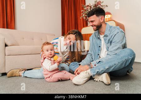 Ein herzerwärmender Familienmoment, in dem Eltern freudig mit ihrem liebenswerten Baby interagieren und dauerhafte Erinnerungen voller Lachen und Lachen schaffen Stockfoto
