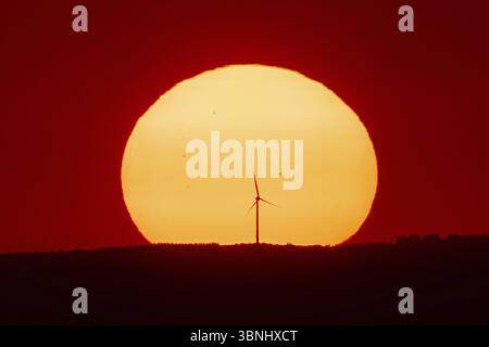Vom Gipfelplateau des Großen Feldbergs im Taunus aus können Sie den Sonnenuntergang hinter einer Windturbine am fernen Horizont Hessen beobachten Stockfoto