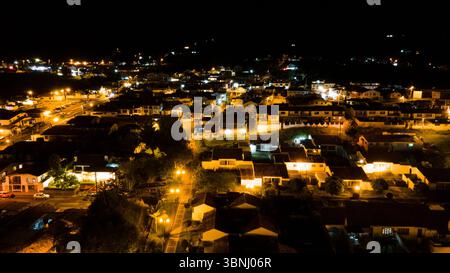 Ein atemberaubender Blick aus der Luft auf Guatavita, Kolumbien, mit beleuchteten Straßen und Häusern vor dem Nachthimmel. Stockfoto