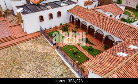 Atemberaubender Blick aus der Luft auf einen traditionellen Innenhof in Guatavita, Kolumbien, mit gemauerten Wegen und grünen Gärten. Stockfoto