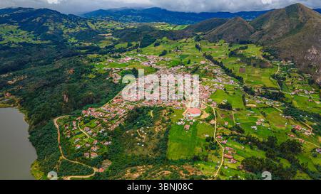 Atemberaubende Aussicht aus der Vogelperspektive auf Guatavita, Kolumbien, mit üppigen grünen Landschaften, traditionellen Häusern und der ruhigen Laguna de Guatavita. Stockfoto