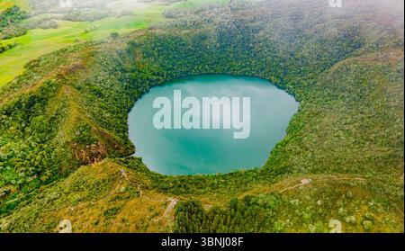 Atemberaubender Blick aus der Vogelperspektive auf die Laguna de Guatavita, umgeben von üppigem Grün, zeigt die natürliche Schönheit von Cundinamarca, Kolumbien. Stockfoto