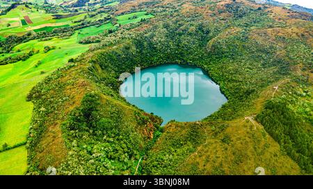 Atemberaubende Aussicht auf die Laguna de Guatavita, umgeben von üppigem Grün und sanften Hügeln in Cundinamarca, Kolumbien. Eine malerische Naturlandschaft. Stockfoto