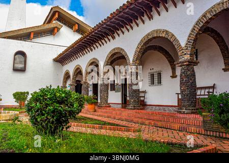 Ein malerischer Innenhof mit traditioneller kolumbianischer Architektur, lebhaftem Grün und Bogensteinstützen in Guatavita, Cundinamarca. Stockfoto