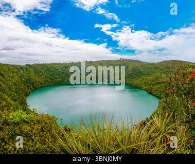 Atemberaubender Panoramablick auf den Guatavita-See, umgeben von üppigem Grün und einem lebendigen Himmel in Cundinamarca, Kolumbien. Stockfoto