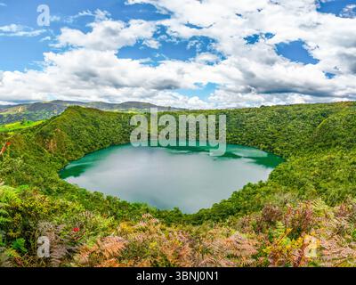 Atemberaubende Aussicht auf die Laguna de Guatavita, umgeben von üppigem grünen Dschungel und wunderschönen Wolken am Himmel, die Kolumbiens natürliche Schönheit zeigen. Stockfoto