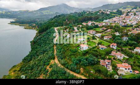 Atemberaubender Blick aus der Luft auf Guatavita, Kolumbien, mit üppigem Grün und ruhigem Lake Guatavita, umgeben von charmanten Häusern. Stockfoto