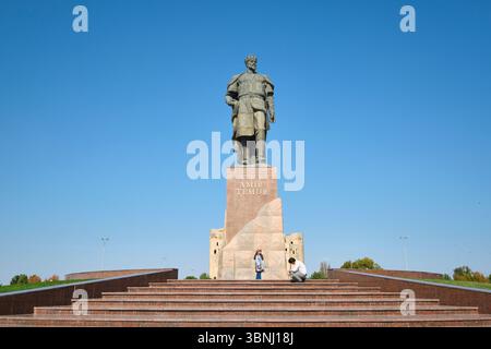 Eine typische Szene, in der ein Paar vor dem Bild posiert. An der riesigen Skulptur Amir Timur, Statue des Führers in Shahrisabz, Usbekistan. Stockfoto