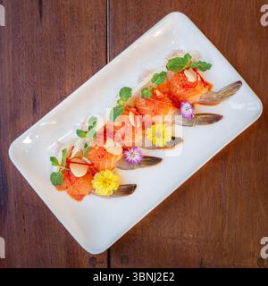 Ein wunderschön gestaltetes japanisches Hot Pot (Shabu Shabu) Set mit dünn geschnittenem Schweinefleisch, das in Blütenform auf einem schwarzen Tablett angeordnet ist, umgeben von Stockfoto