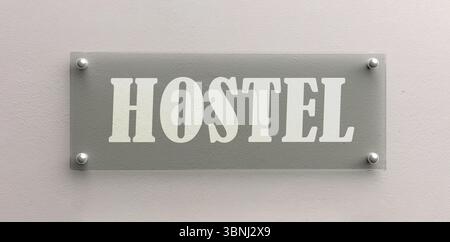 Das Glasschild DES HOSTELS ist an der weißen Wand verschraubt Stockfoto