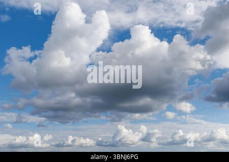 Ein landschaftlich schöner Himmel mit einer Mischung aus dunklen und flauschigen Wolken, die eine dramatische und dynamische Atmosphäre mit blauen Flecken schaffen. Stockfoto