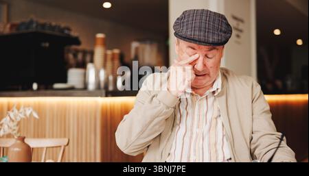 Seniorenmann, traurig und morgens im Café, einsam und unglücklich mit Nostalgie im Ruhestand. Ältere Menschen, Gäste und Weinen im Bistro mit Nachdenken Stockfoto