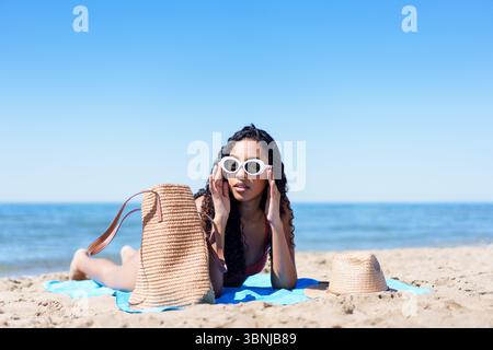 Entspannen am Strand Eine modische junge Frau, die die warme Sonne genießt Stockfoto