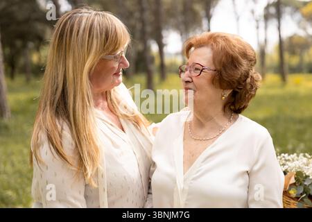 Ein berührender Moment zwischen Mutter und Tochter, die sich im Freien eine warme Umarmung teilen, symbolisiert Familienliebe und -Verbindung. Sie stehen zusammen Stockfoto