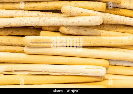 Aus nächster Nähe sehen Sie goldene, knusprige Brotstangen, die ordentlich gestapelt sind. Die Textur dieser Brotstäbchen macht sie perfekt für die Verwendung als natürlicher Lebensmittelhintergrund Stockfoto