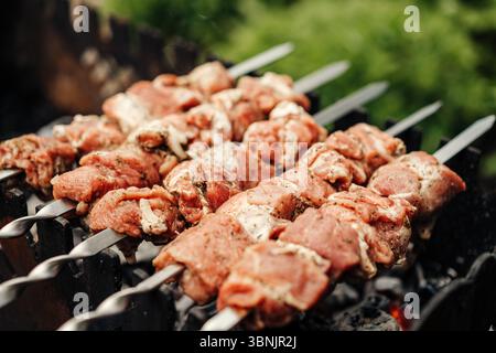 Saftige gegrillte Fleischspieße brutzeln in dieser Nahaufnahme über einem Holzkohlegrill. Es fängt die Essenz des traditionellen Schaschliks perfekt ein und ist ideal für s Stockfoto