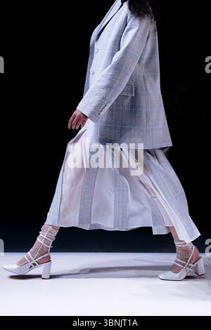 Frau mit Tweedjacke und weißem Rock, klassische Mode-Kleidung auf schwarzem Hintergrund Stockfoto